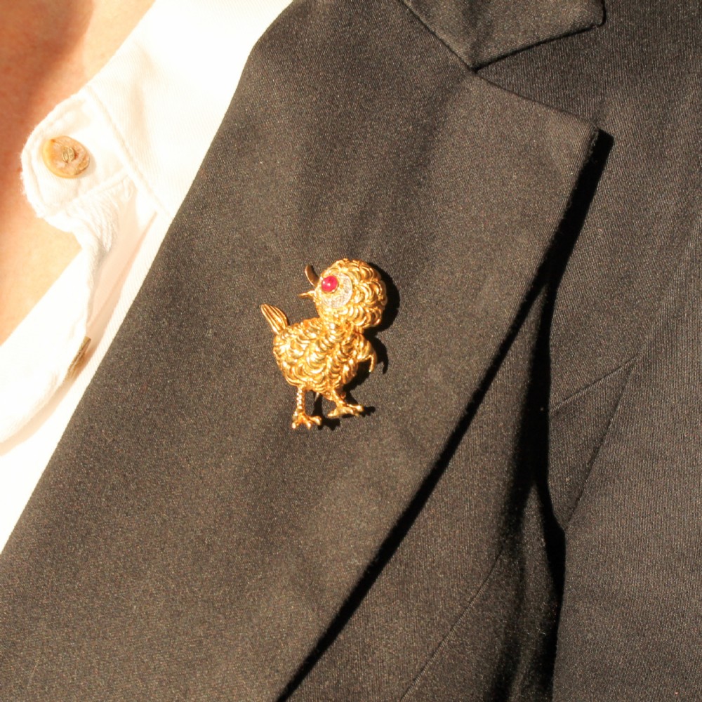 A textured yellow gold chick brooch featuring a cabochon ruby eye framed by small diamonds. View VII