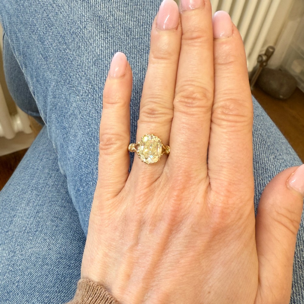 An antique yellow gold solitaire ring featuring a large light yellow old cut diamond in a multi-claw setting with split shoulders. View VI