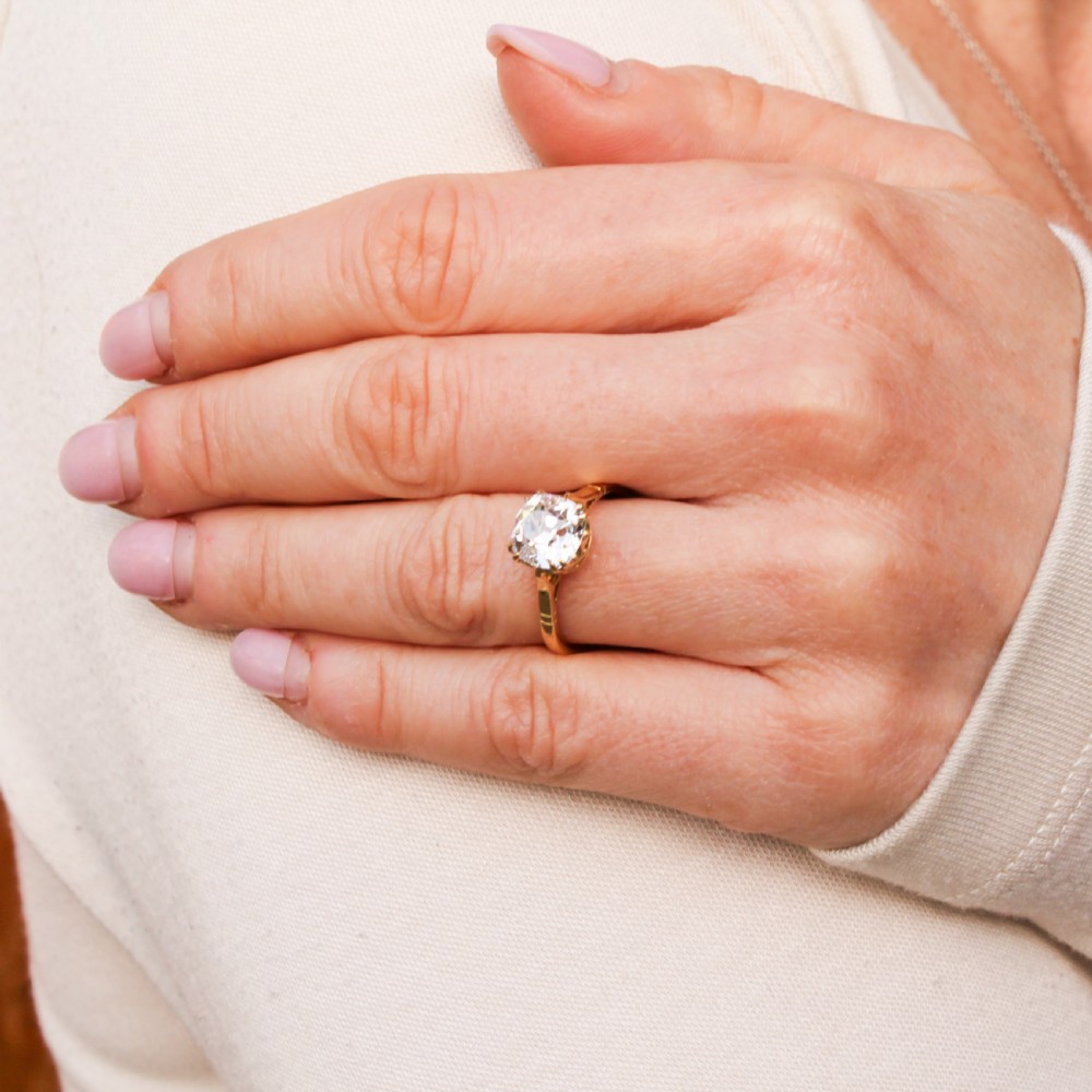 An antique yellow gold solitaire ring featuring a cushion-shaped old cut diamond in a claw setting. View IX