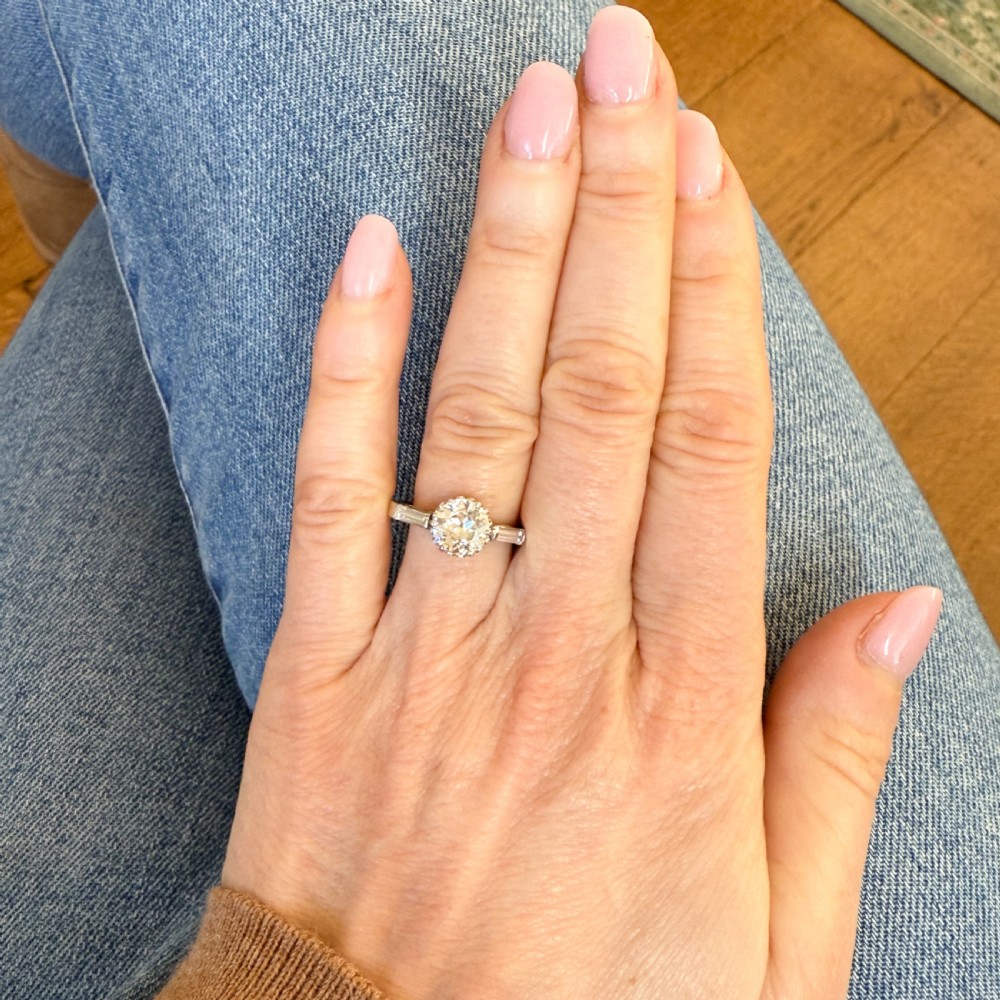 A vintage platinum engagement ring featuring a central round old cut diamond flanked by two tapered baguette diamonds. View VII