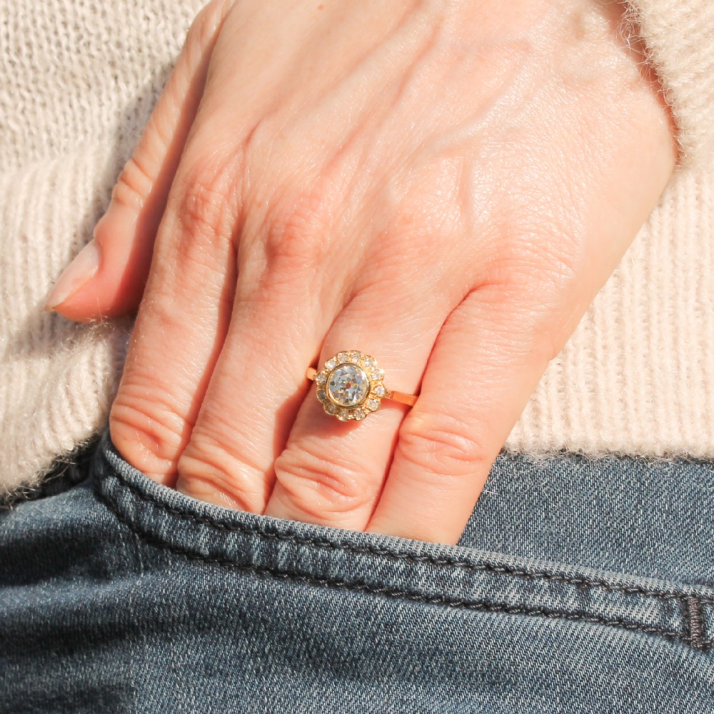 A yellow gold ring featuring a central old cut diamond in a bezel setting surrounded by a scalloped halo of smaller accent diamonds. View II