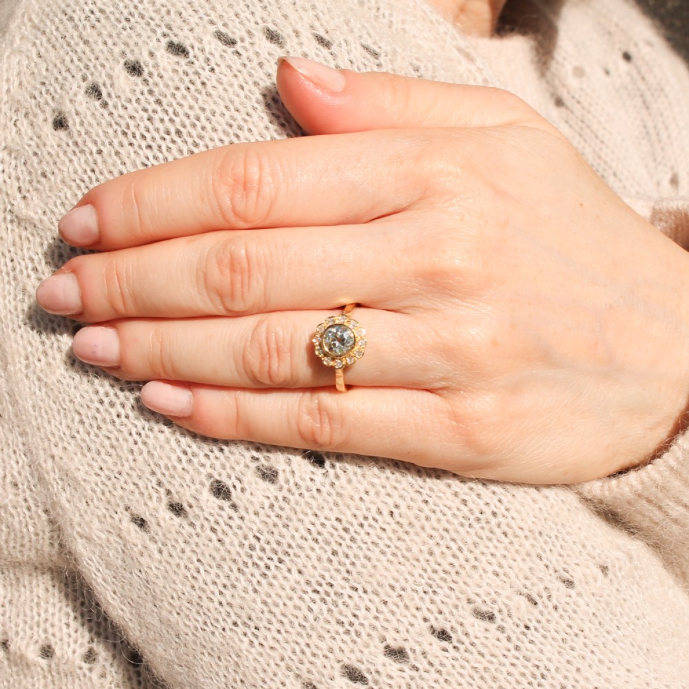 A yellow gold ring featuring a central old cut diamond in a bezel setting surrounded by a scalloped halo of smaller accent diamonds. View VII