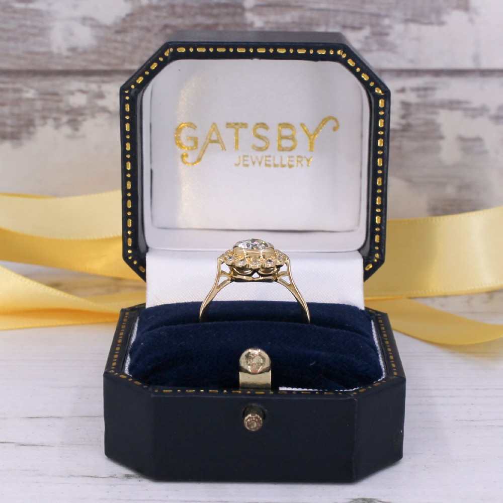 A yellow gold ring featuring a central old cut diamond in a bezel setting surrounded by a scalloped halo of smaller accent diamonds. View IX