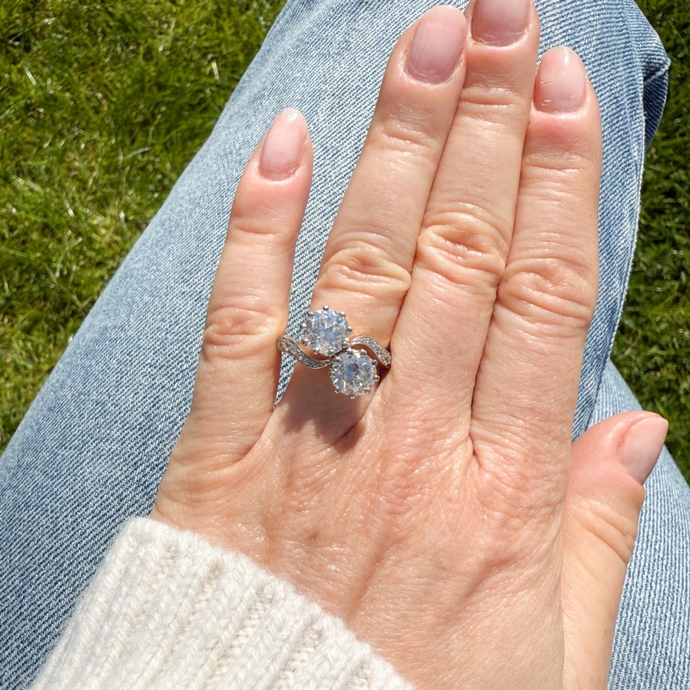 A vintage two-stone diamond Toi et Moi ring featuring two old European cut diamonds set in claw settings with a yellow gold band and diamond-paved shoulders. View VI