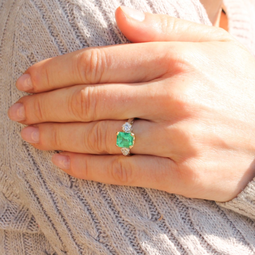 A vintage gold ring set with a rectangular central emerald-cut green gemstone and two flanking round brilliant diamonds. View II
