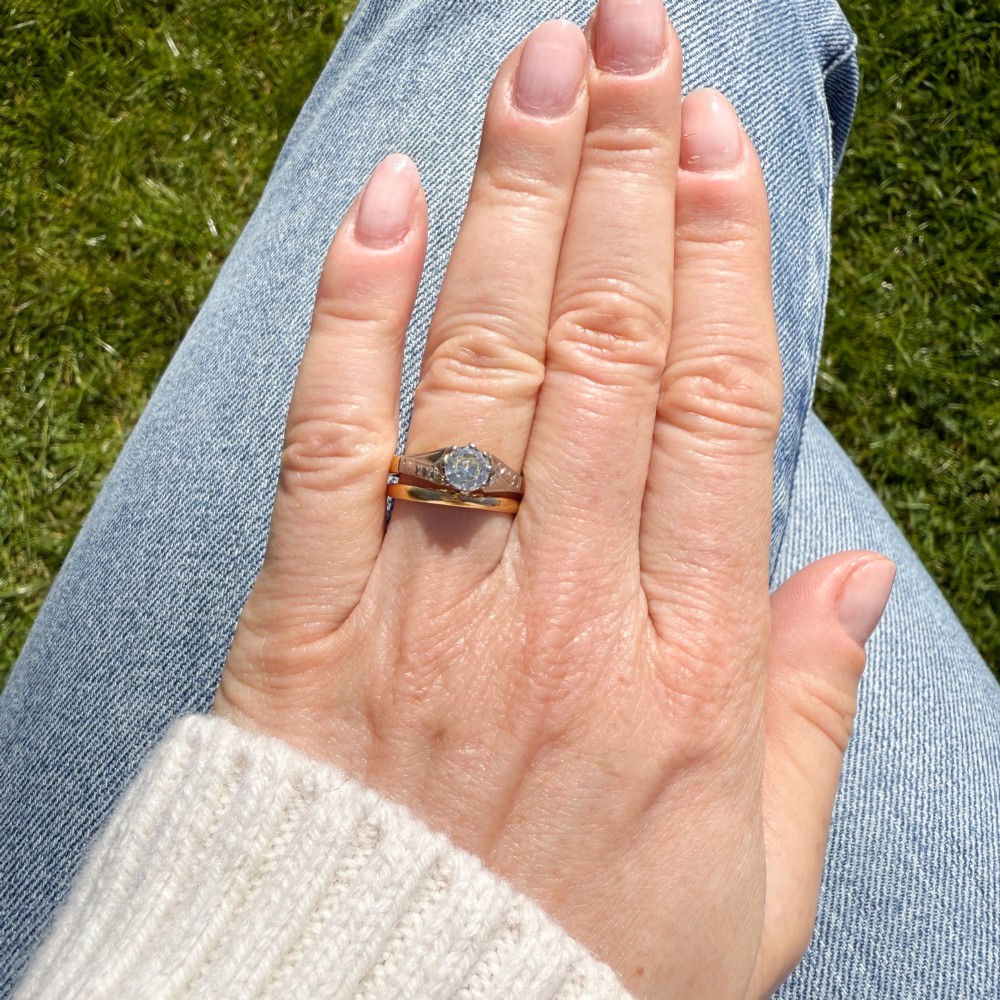A vintage yellow gold solitaire engagement ring featuring a round brilliant cut diamond set in white metal claws with carved shoulders. View VII