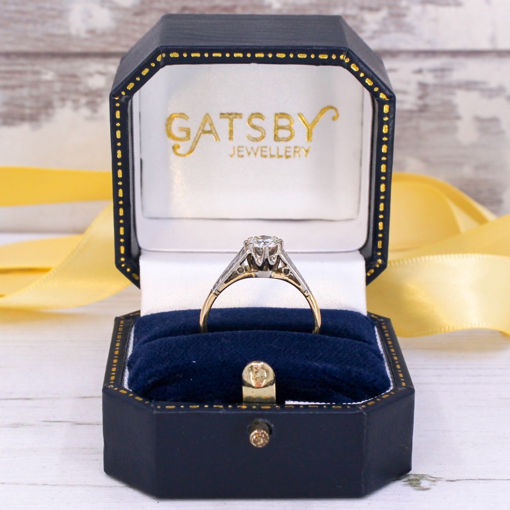 A vintage yellow gold solitaire engagement ring featuring a round brilliant cut diamond set in white metal claws with carved shoulders. View IX
