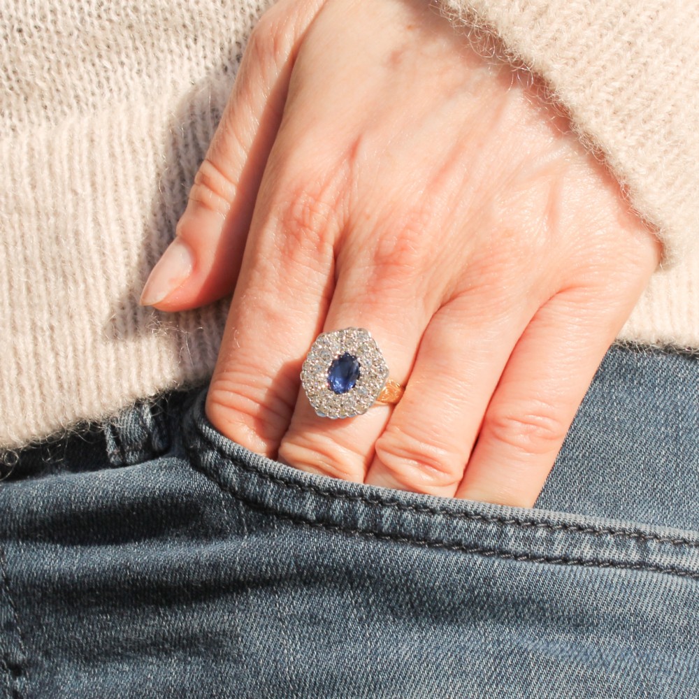 An oval blue sapphire surrounded by a double halo of diamonds set in a scalloped white metal mount on an engraved yellow gold band. View II