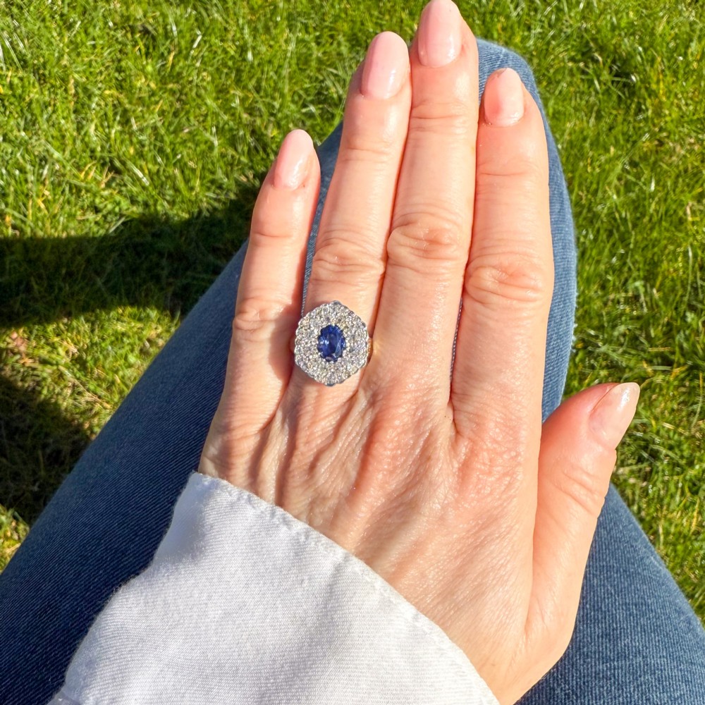 An oval blue sapphire surrounded by a double halo of diamonds set in a scalloped white metal mount on an engraved yellow gold band. View VI
