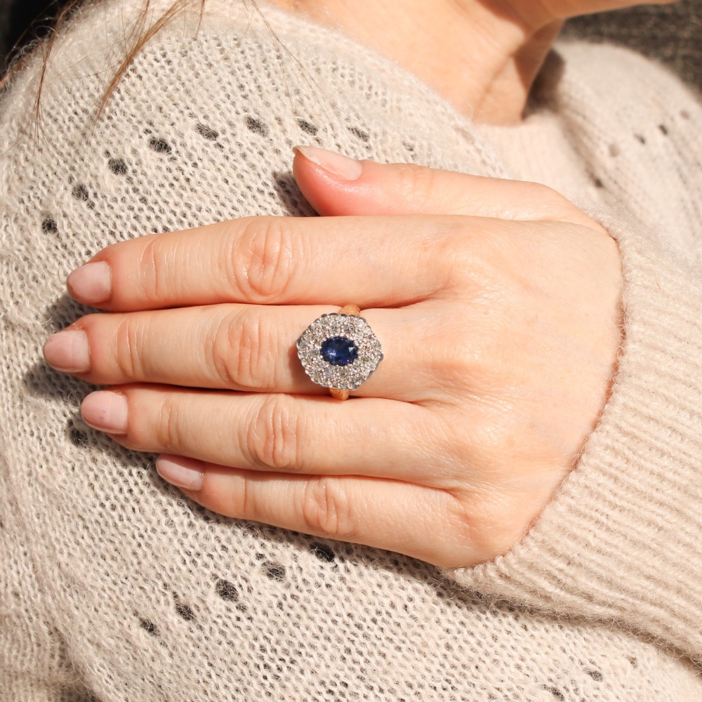 An oval blue sapphire surrounded by a double halo of diamonds set in a scalloped white metal mount on an engraved yellow gold band. View VII