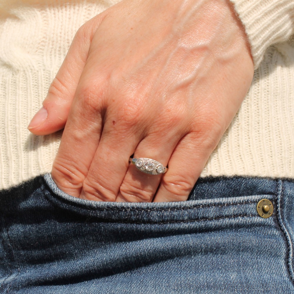 A vintage Art Deco white metal ring featuring a central old cut diamond flanked by two smaller diamonds in an elongated milgrained setting. View II