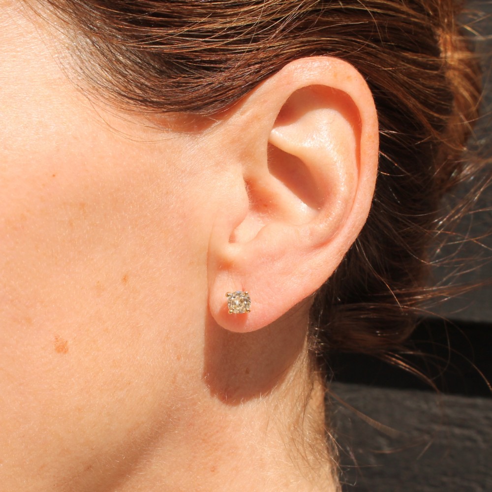 A pair of 18k yellow gold stud earrings featuring claw-set old mine cut diamonds. View IV