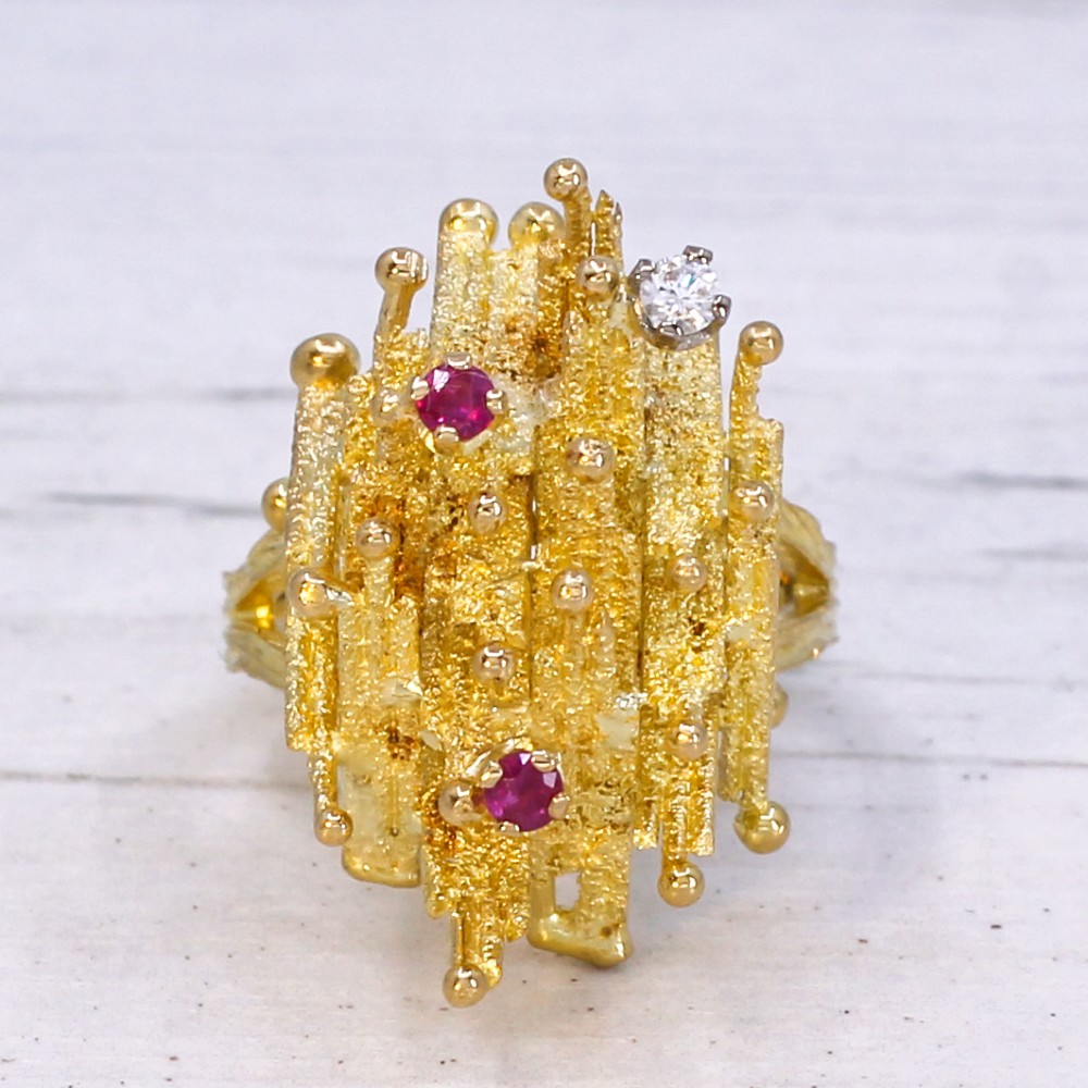 A 1960s textured yellow gold ring featuring an abstract lattice structure set with two round rubies and a single clear diamond. View III
