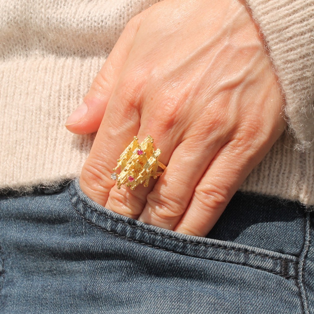 A 1960s textured yellow gold ring featuring an abstract lattice structure set with two round rubies and a single clear diamond. View VIII