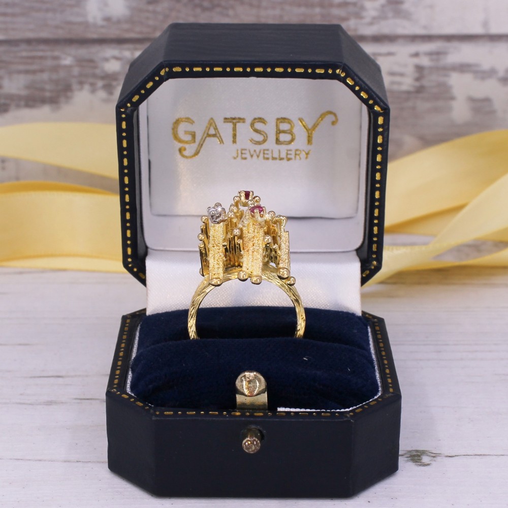A 1960s textured yellow gold ring featuring an abstract lattice structure set with two round rubies and a single clear diamond. View IX