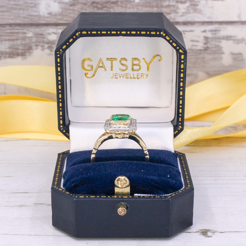 A vintage gold ring featuring a central rectangular green emerald surrounded by a halo of small diamonds. View IX