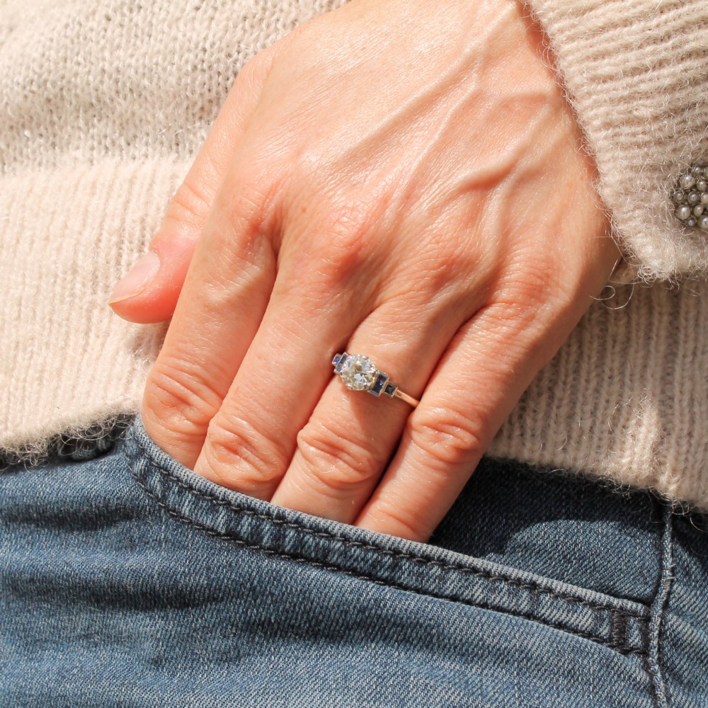A platinum ring featuring a central round old cut diamond flanked by stepped calibre-cut blue sapphires. View VII