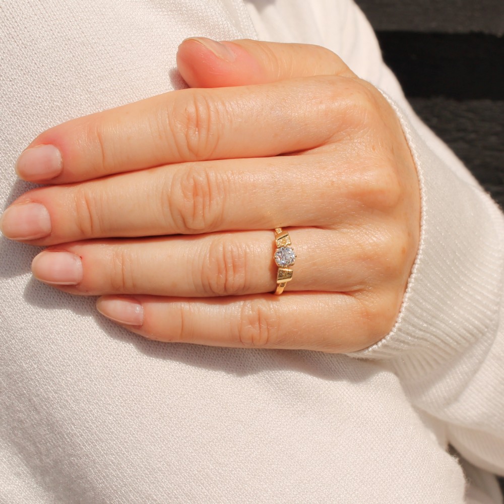 A yellow gold Art Deco engagement ring featuring a central round old cut diamond flanked by geometric stepped shoulders set with small accent diamonds. View VII