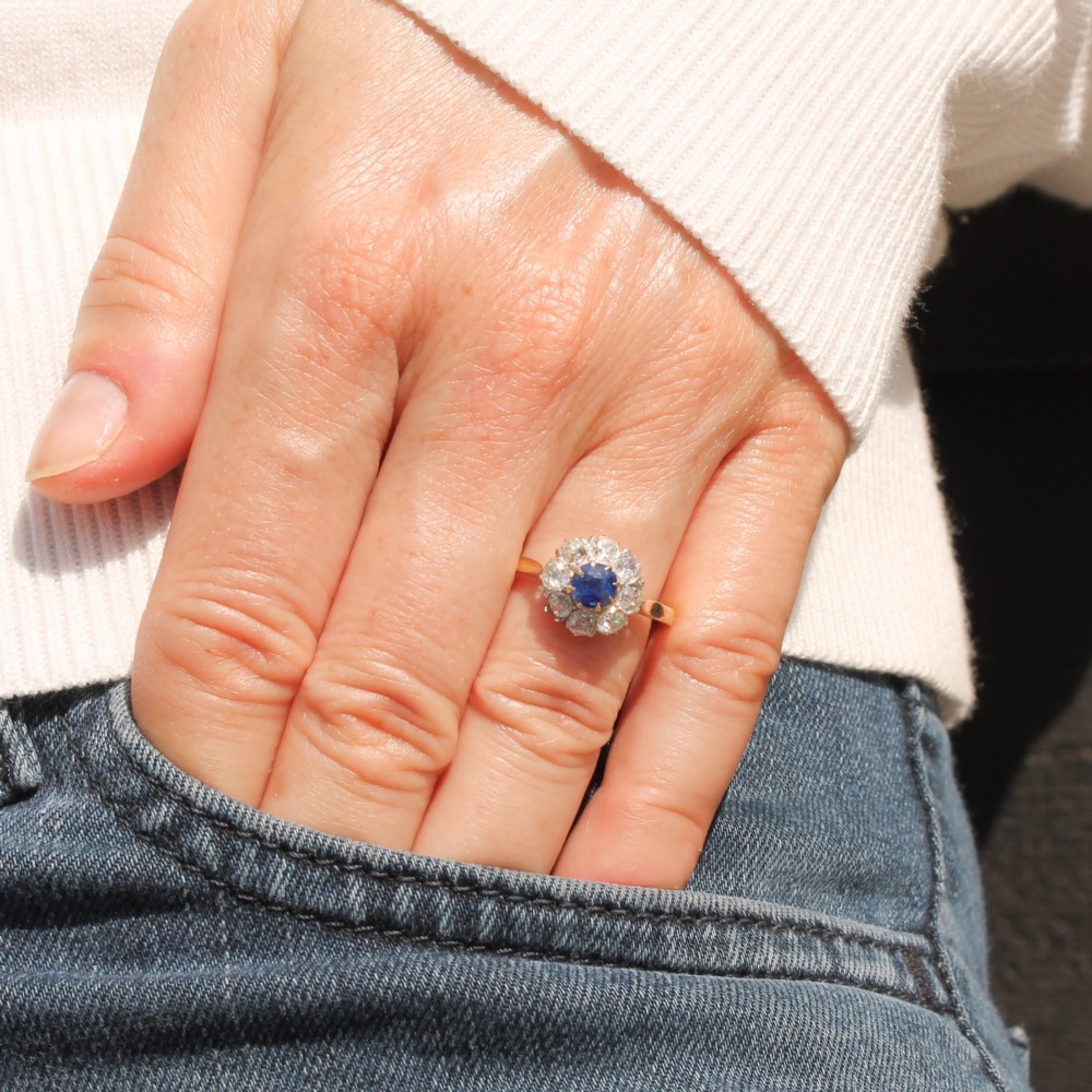 A vintage cluster ring featuring a central round blue sapphire encircled by nine brilliant-cut diamonds set on a yellow gold band. View II