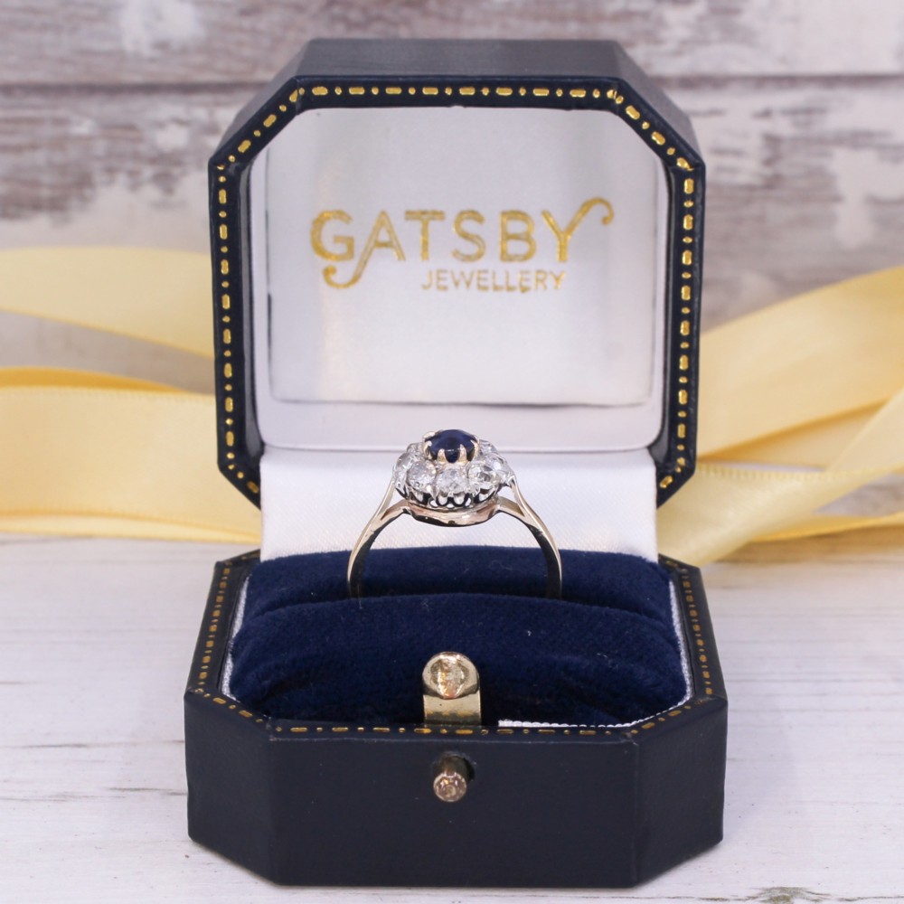 A vintage cluster ring featuring a central round blue sapphire encircled by nine brilliant-cut diamonds set on a yellow gold band. View IX