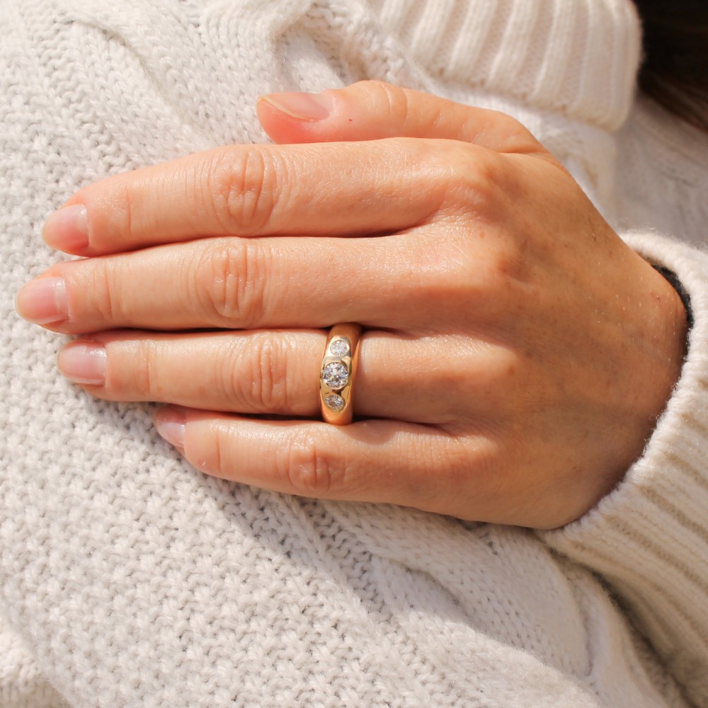 A thick yellow gold ring featuring three flush-set round diamonds embedded across the top band. View II