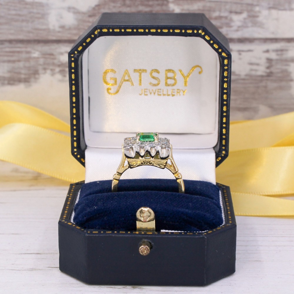 A vintage 1950s dress ring featuring a square green emerald framed by a square halo of diamonds set in a yellow gold band. View IX