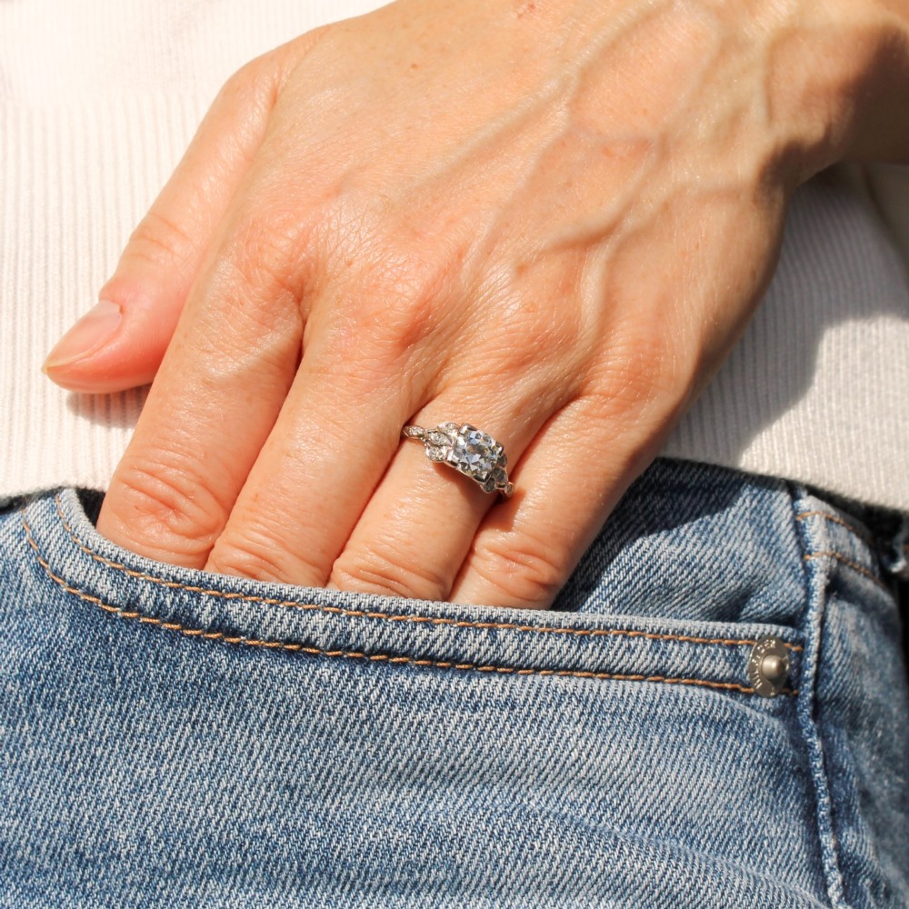 An Edwardian platinum ring featuring a central old cut diamond within pierced filigree shoulders and an engraved band. View II