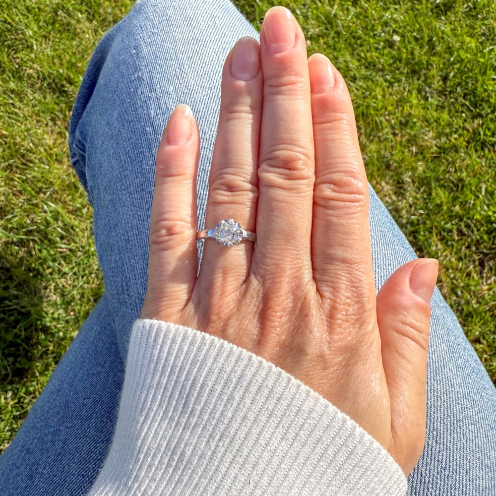 A mid-century white metal solitaire engagement ring featuring a central old cut diamond in a multi-claw raised setting. View VI