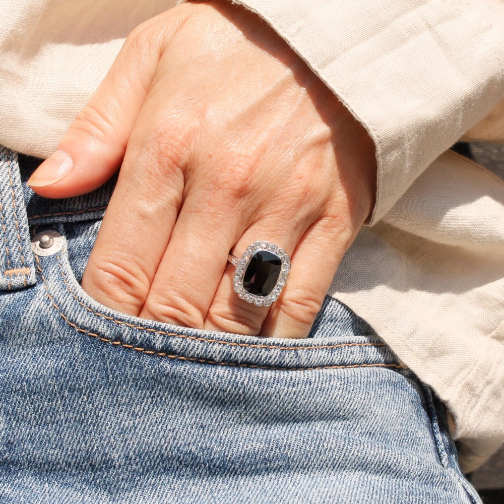 A vintage platinum ring featuring a cushion-cut dark blue sapphire encircled by a halo of brilliant-cut diamonds. View VII