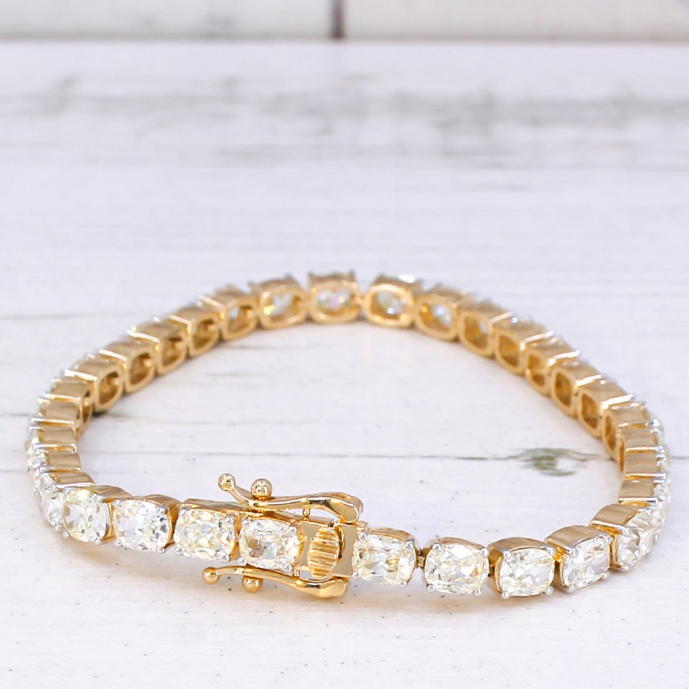 A yellow gold tennis bracelet set with a continuous row of cushion-shaped old mine cut diamonds featuring claw mounts and a box clasp. View III