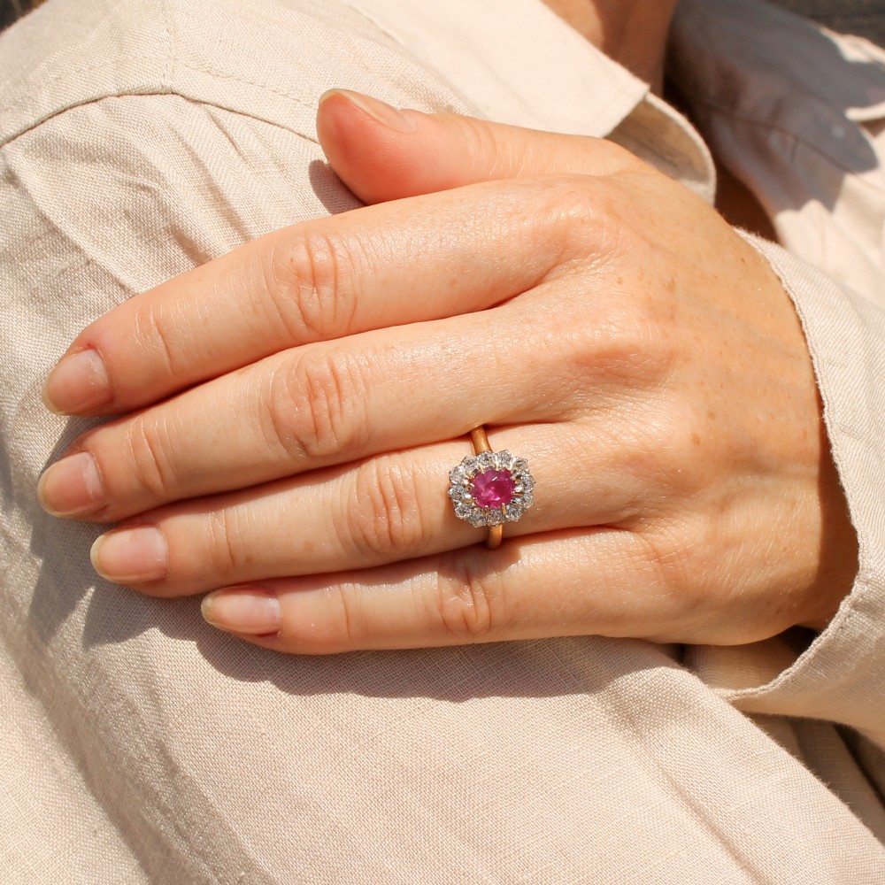 An antique gold ring featuring a central oval pink sapphire set in gold claws, surrounded by a halo of brilliant old-cut diamonds set on a smooth yellow gold band. View VII