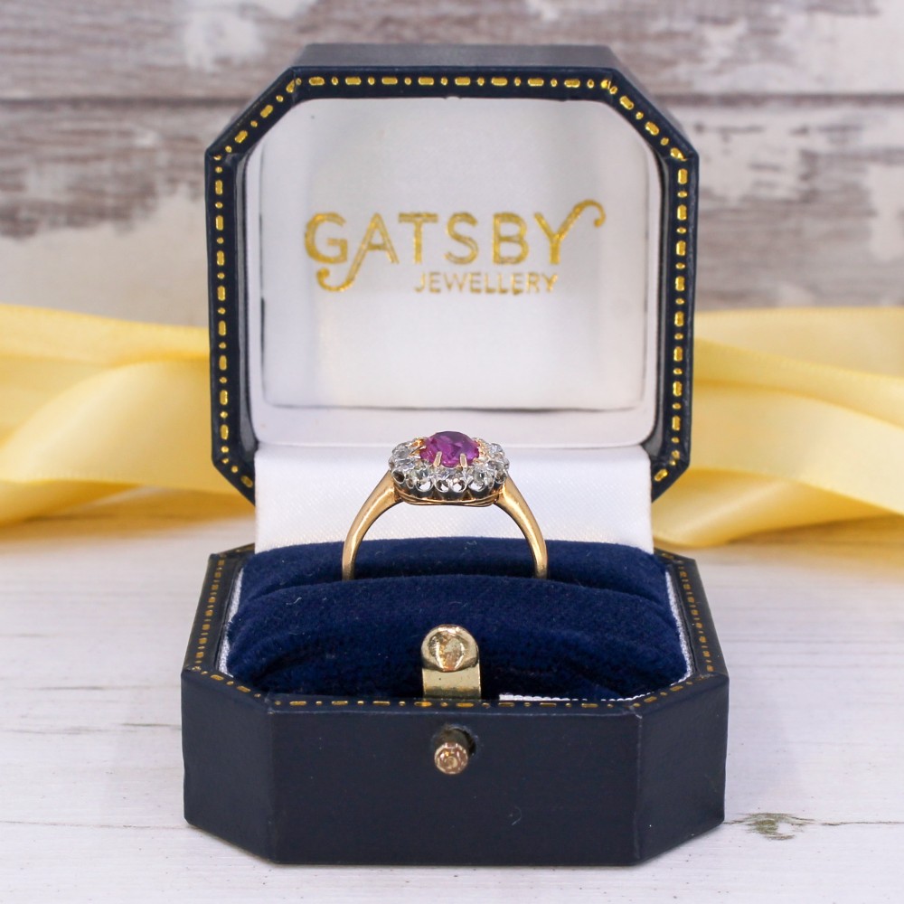 An antique gold ring featuring a central oval pink sapphire set in gold claws, surrounded by a halo of brilliant old-cut diamonds set on a smooth yellow gold band. View IX