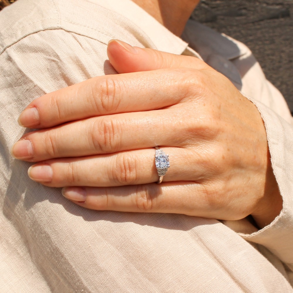 An Art Deco diamond ring featuring a central cushion-shaped old cut diamond mounted in a platinum band with stepped diamond shoulders. View VII
