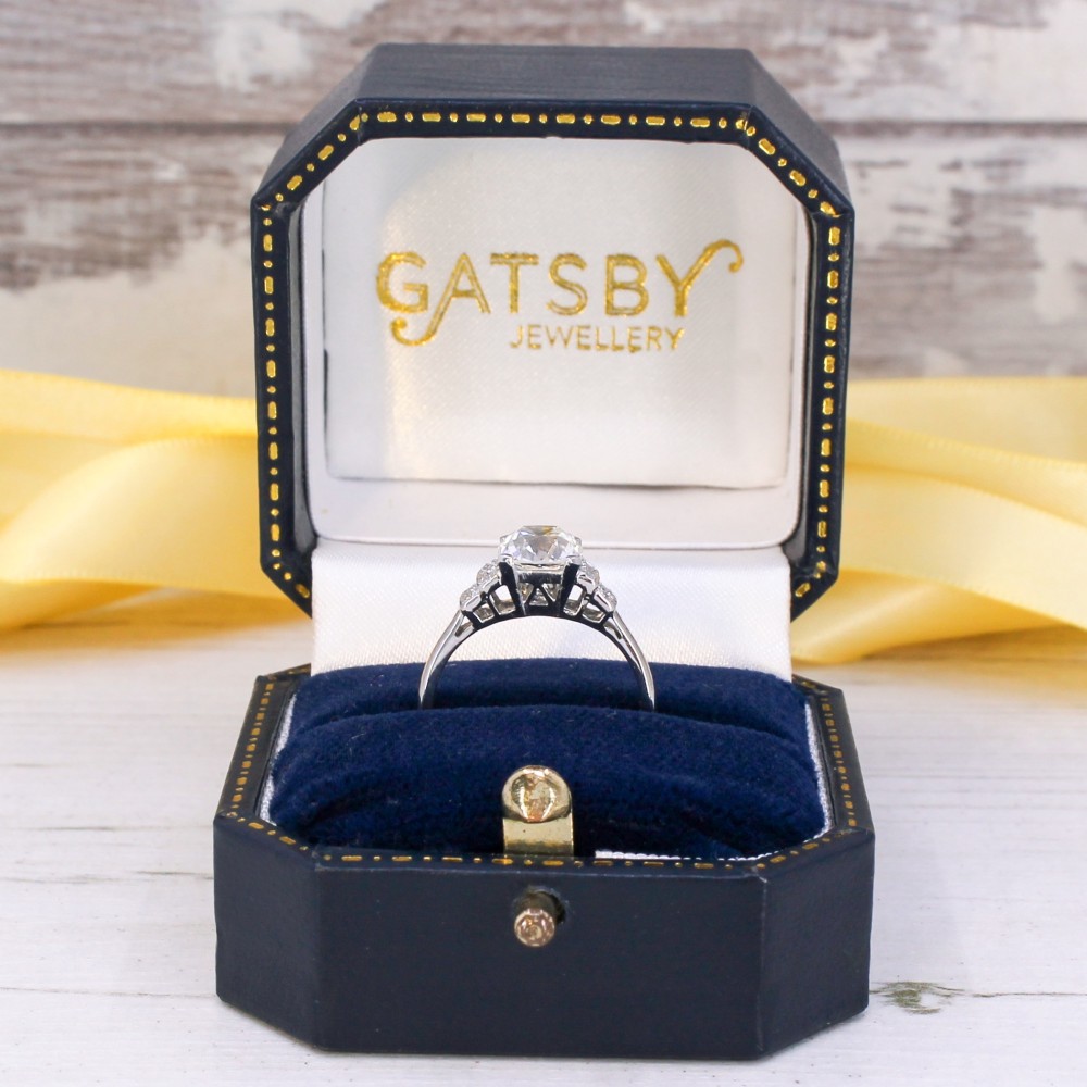 An Art Deco diamond ring featuring a central cushion-shaped old cut diamond mounted in a platinum band with stepped diamond shoulders. View IX