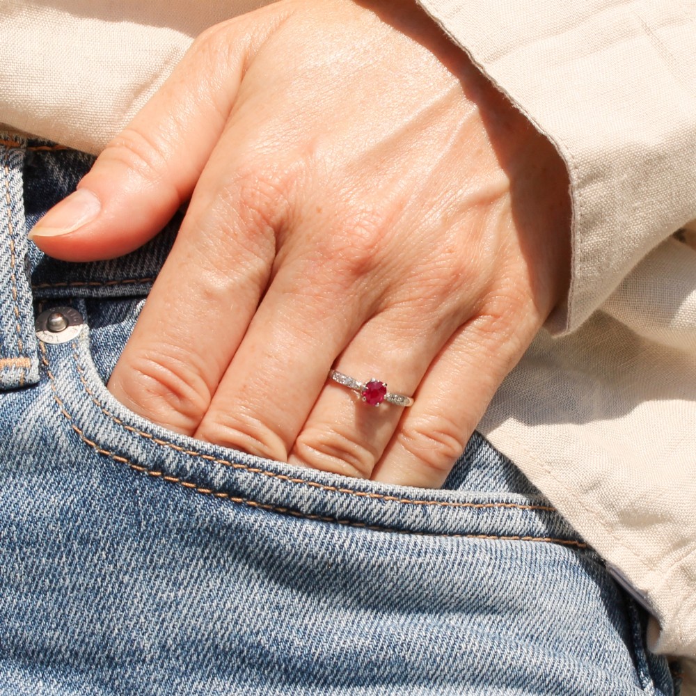 A vintage platinum ring featuring a central round red ruby flanked by diamond-set shoulders. View VII