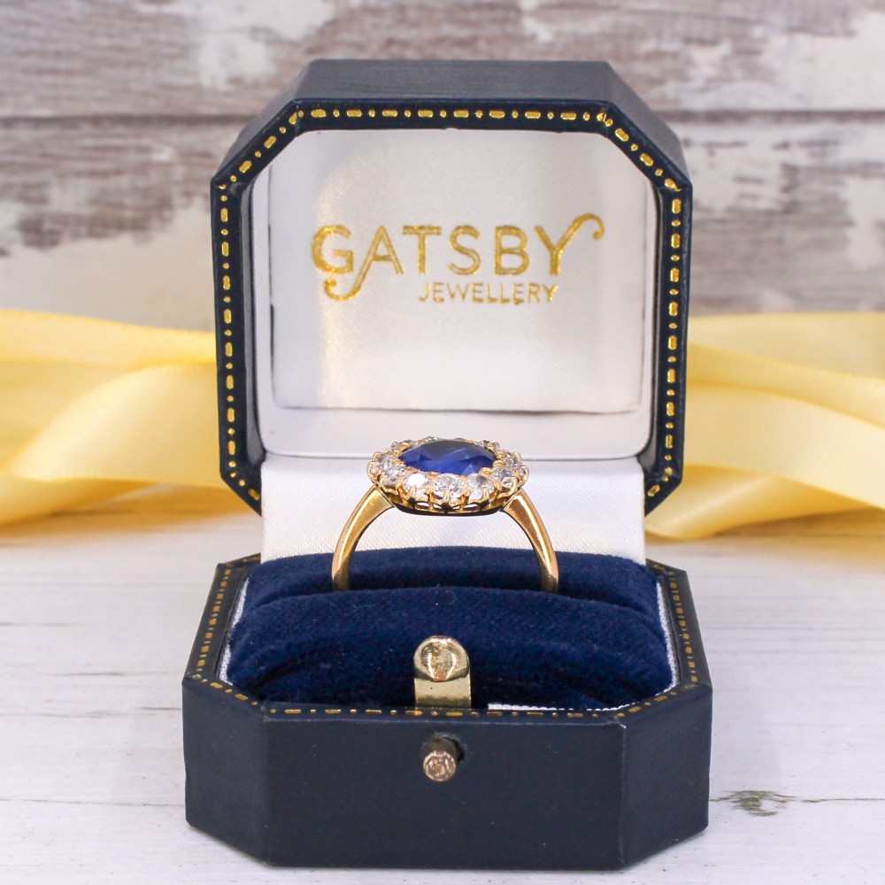 An Edwardian cluster ring set with a circular blue central sapphire framed by a halo of old cut diamonds on a yellow gold band. View IX