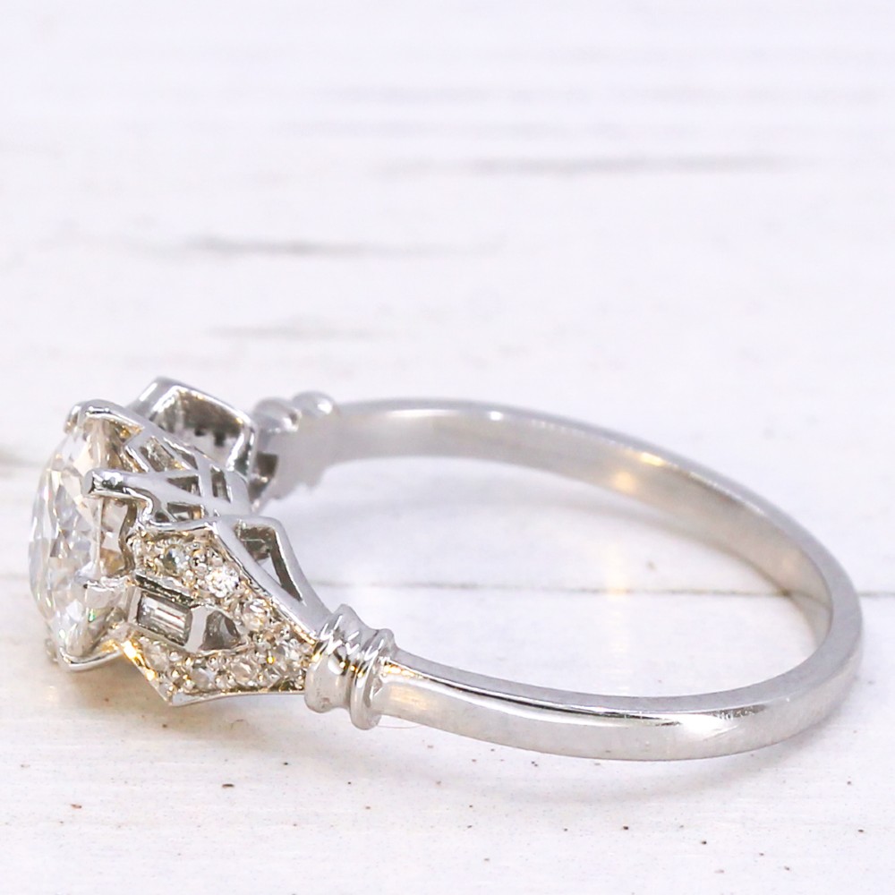 A 1930s platinum engagement ring featuring a central round old cut diamond with geometric accent-set shoulders. View IV
