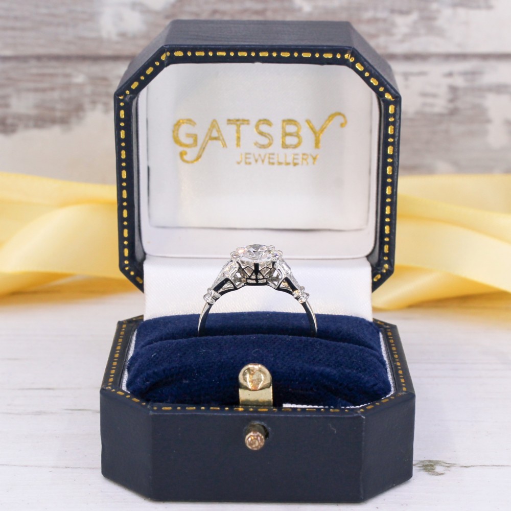 A 1930s platinum engagement ring featuring a central round old cut diamond with geometric accent-set shoulders. View IX