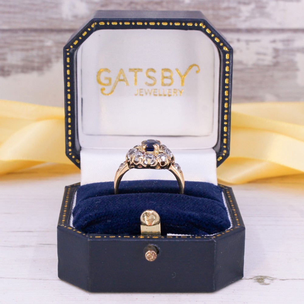 An antique yellow gold ring featuring a central cushion-cut blue sapphire surrounded by a halo of old cut diamonds. View IX