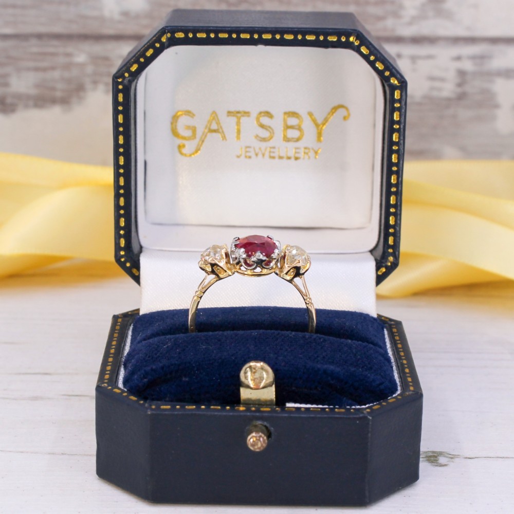 An antique yellow gold ring set with a central oval pinkish-red ruby flanked by two round old cut diamonds in claw settings. View IX