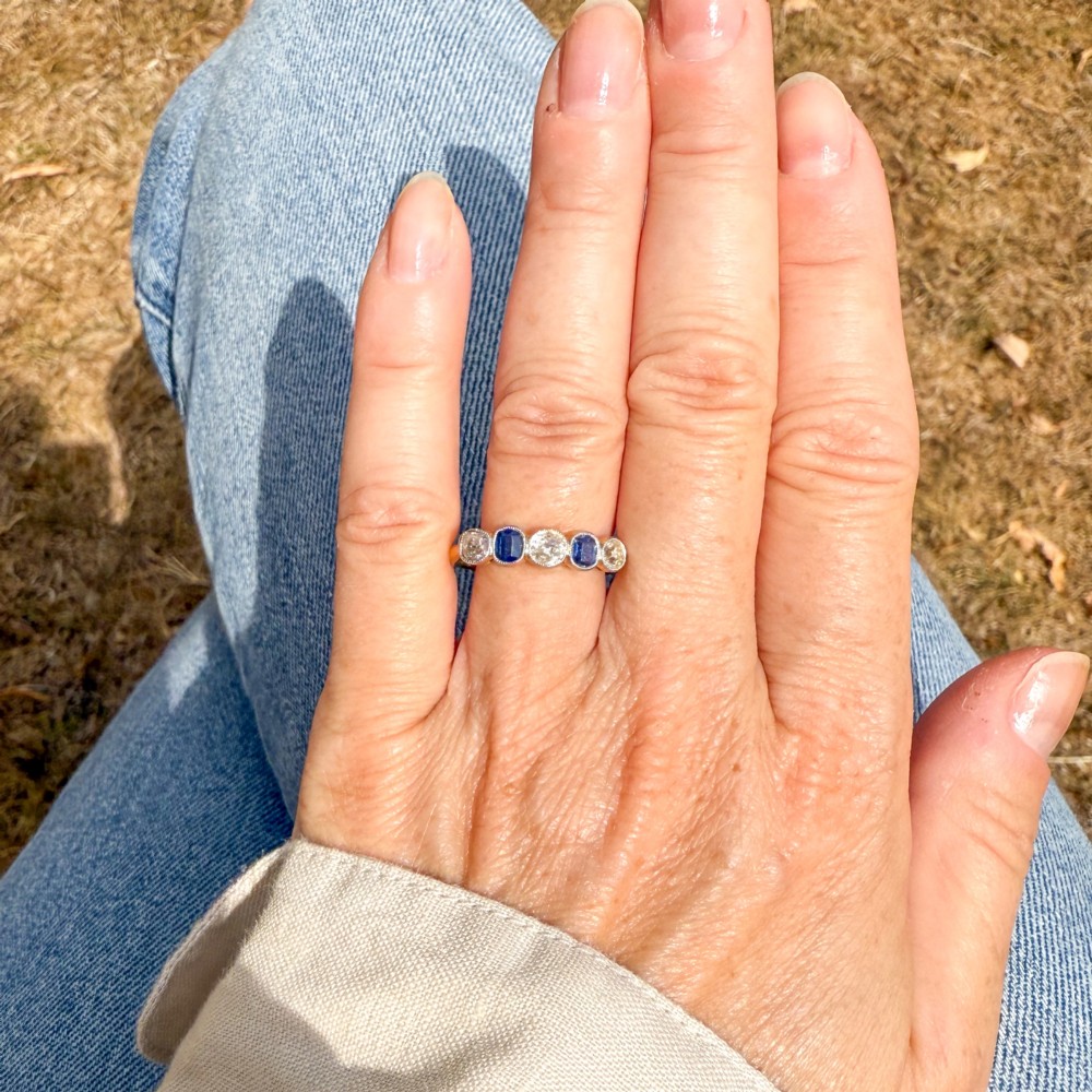 An antique yellow gold ring set with five alternating old cut diamonds and cushion-shaped blue sapphires featuring millegrain details. View VII