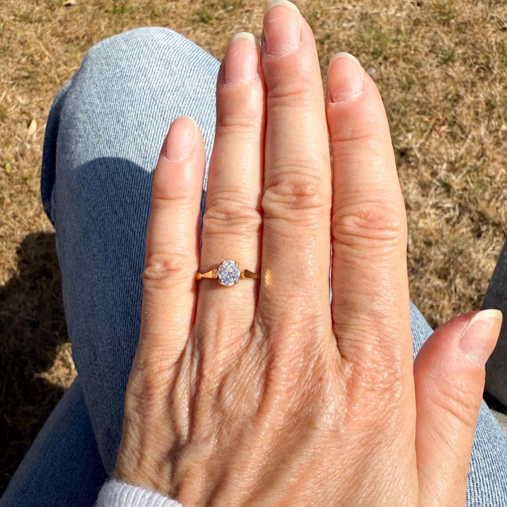 A vintage 1930s yellow gold ring featuring a central claw-set oval cut diamond with tapered shoulders. View VI