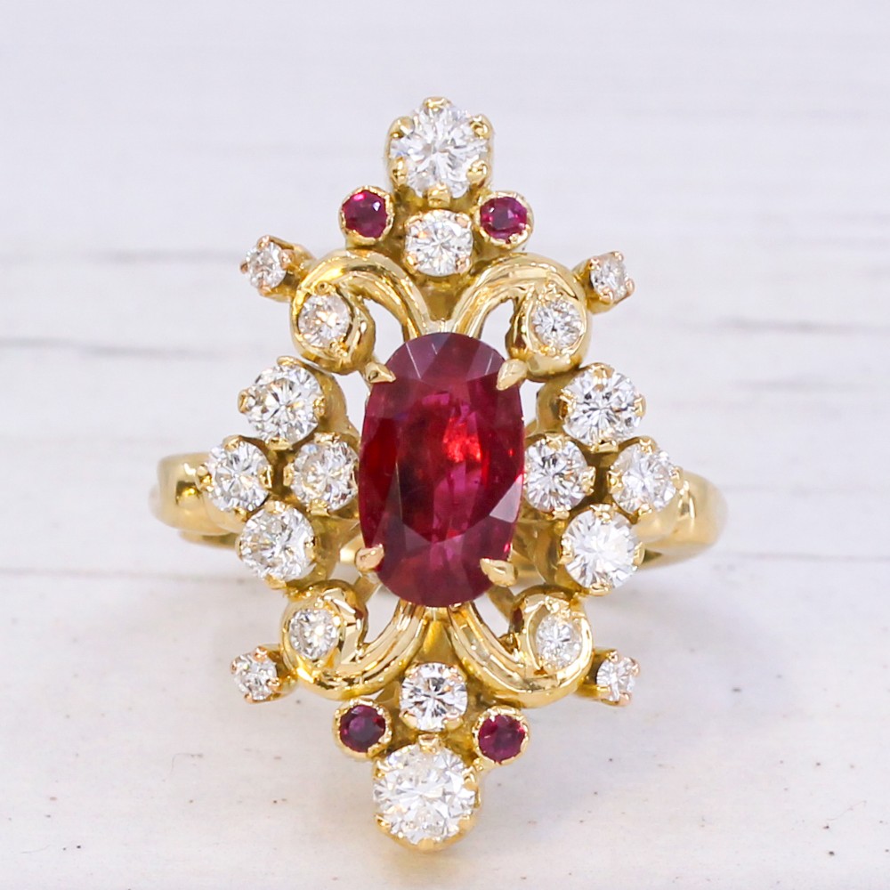 A yellow gold vintage ring featuring an oval red ruby surrounded by openwork scroll motifs set with round diamonds and accent rubies. View III