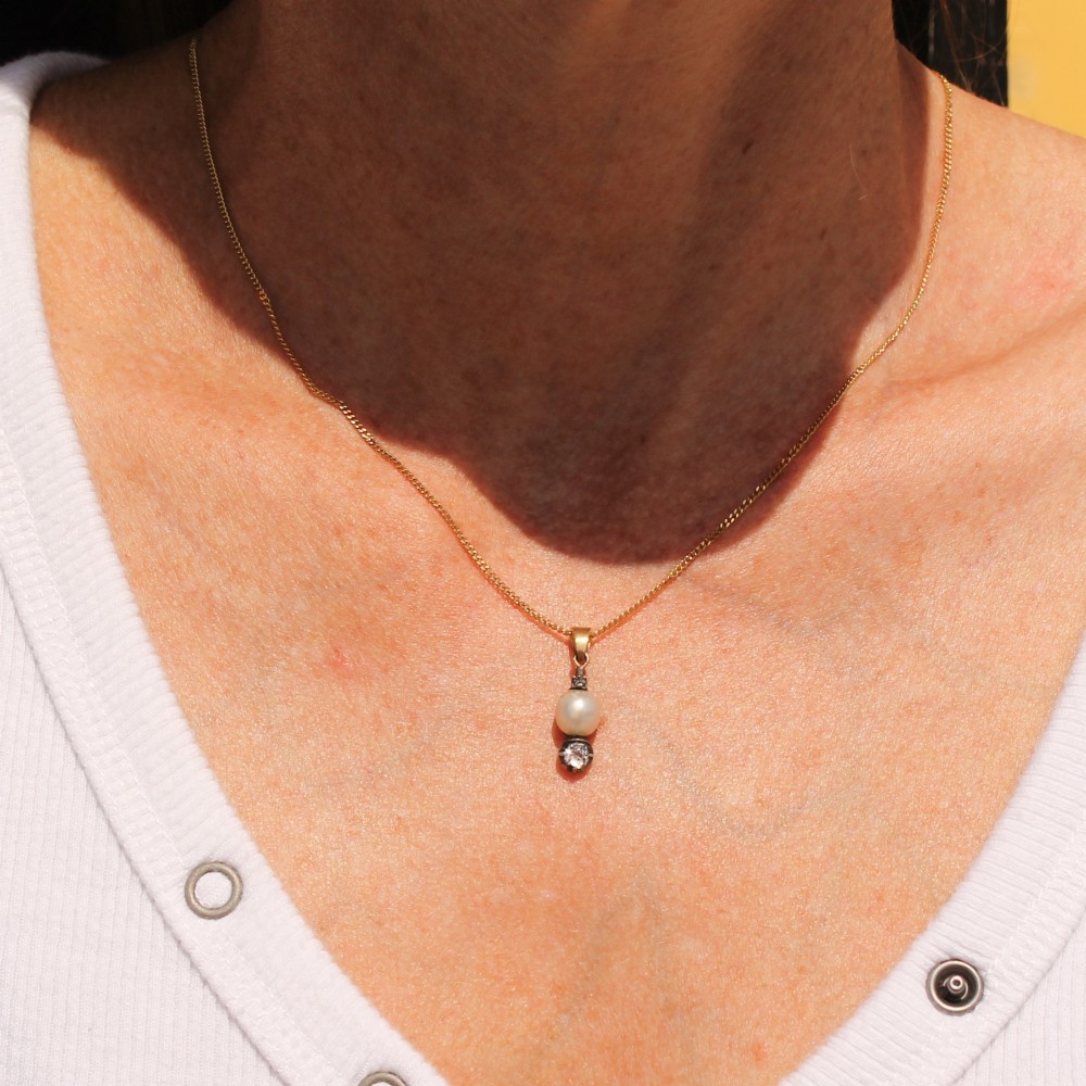 An antique gold chain holding a vertical drop pendant featuring a natural pearl suspended between two bezel-set diamonds. View VIII