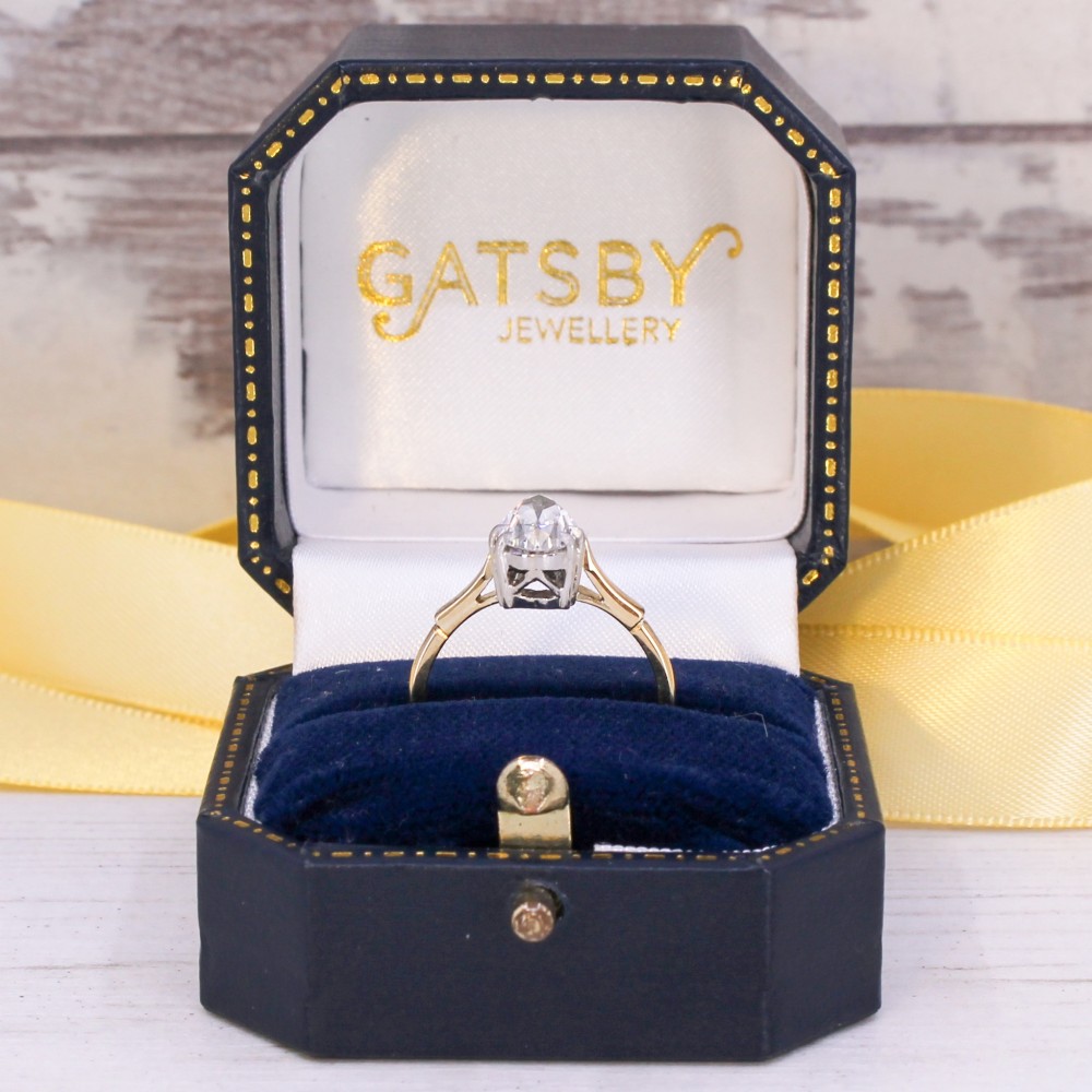 A vintage solitaire ring featuring a pear-cut diamond held in white metal claw settings on a smooth yellow gold band. View IX