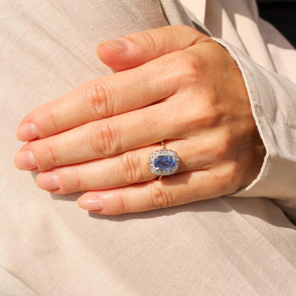 A cushion-cut blue Ceylon sapphire set in a multi-claw setting surrounded by a halo of brilliant white diamonds on a yellow gold band. View VII