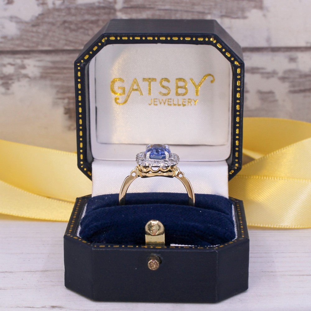 A cushion-cut blue Ceylon sapphire set in a multi-claw setting surrounded by a halo of brilliant white diamonds on a yellow gold band. View IX