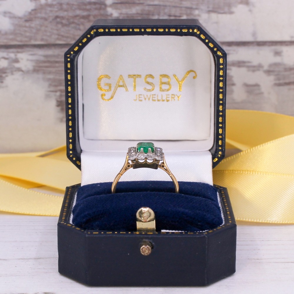 An antique yellow gold ring set with a rectangular central green emerald surrounded by a scalloped halo of small old cut diamonds. View IX