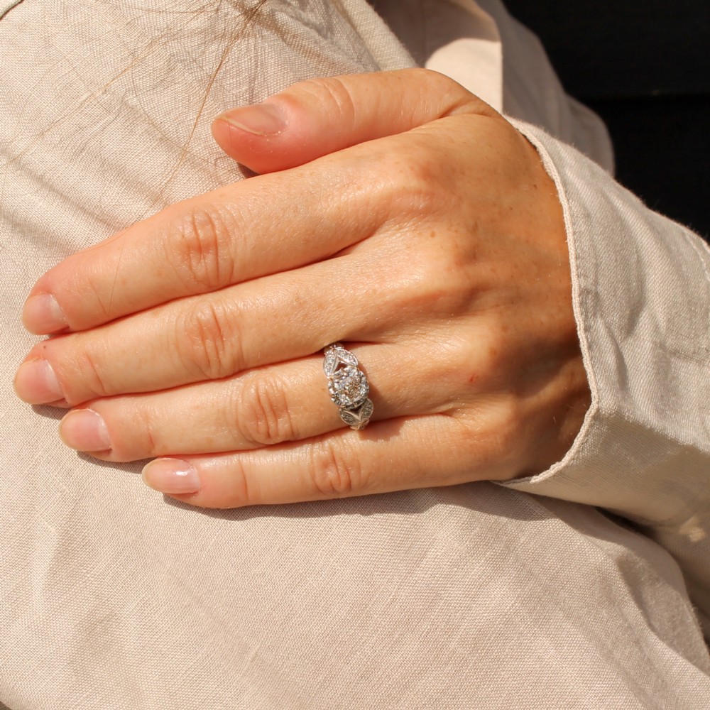 An Art Deco diamond ring featuring a central old cut diamond set in platinum with leaf-motif shoulders on an 18ct yellow gold band. View II