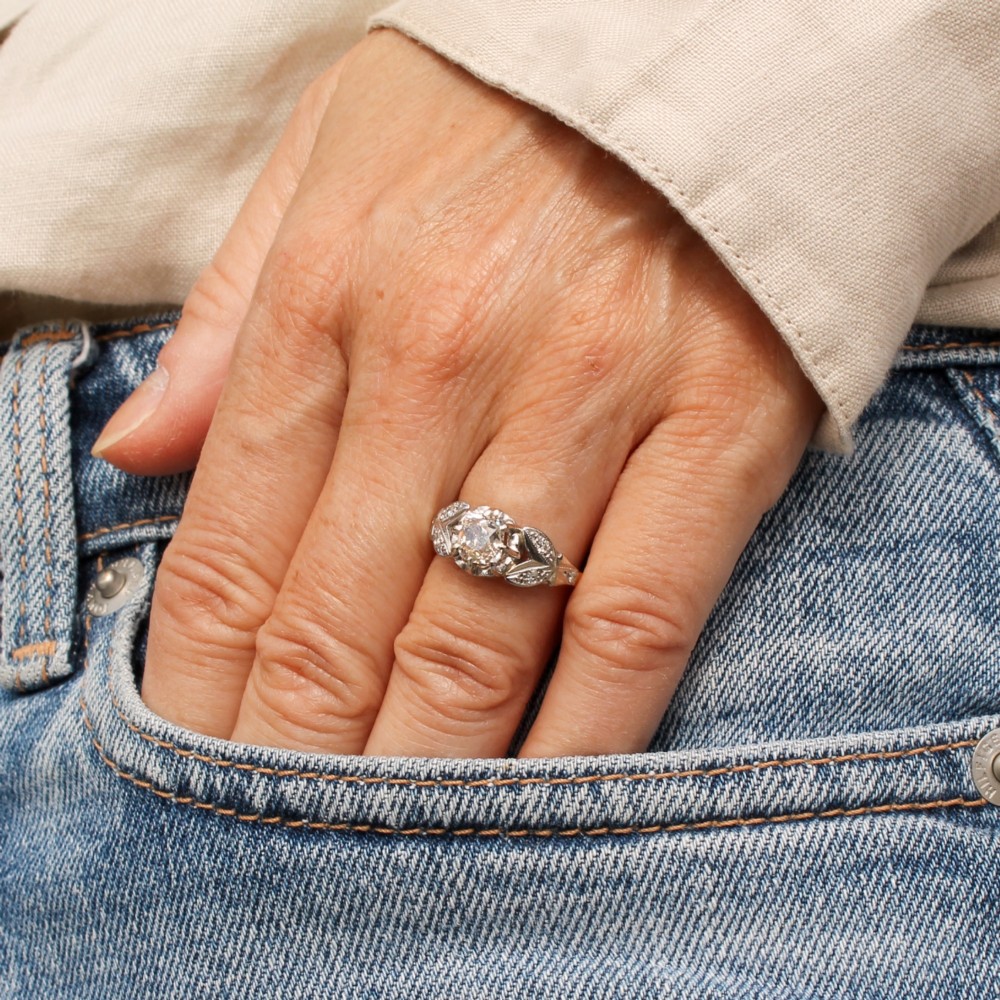 An Art Deco diamond ring featuring a central old cut diamond set in platinum with leaf-motif shoulders on an 18ct yellow gold band. View VII
